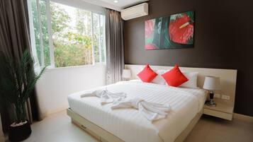 Habitación de hotel con una cama grande, una planta en maceta, una ventana con cortinas, un aire acondicionado de pared y un cuadro.