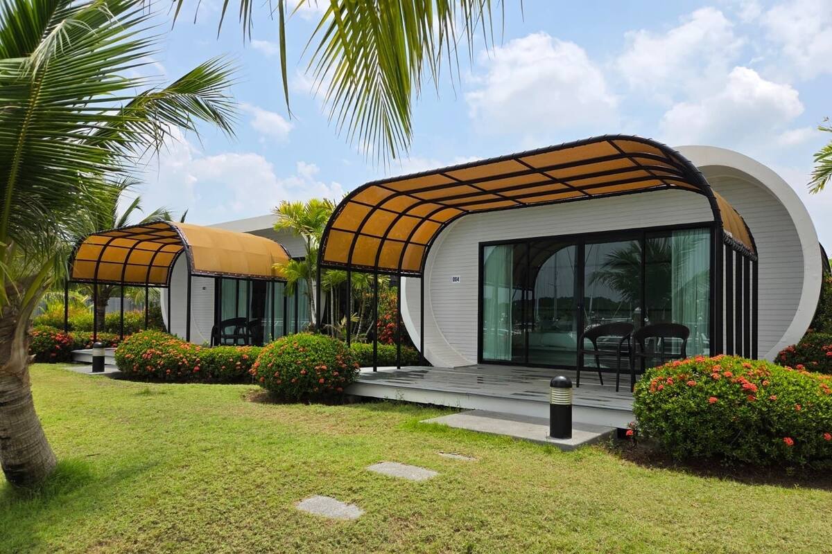 A modern building with curved architecture, a covered outdoor seating area, and a well-maintained garden.
