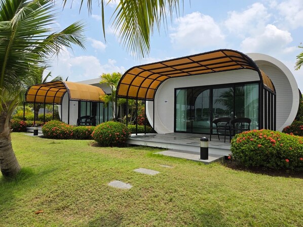 Un bâtiment moderne à l’architecture aux lignes courbes, doté d’un espace extérieur aménagé et abrité, ainsi que d’un jardin bien entretenu.
