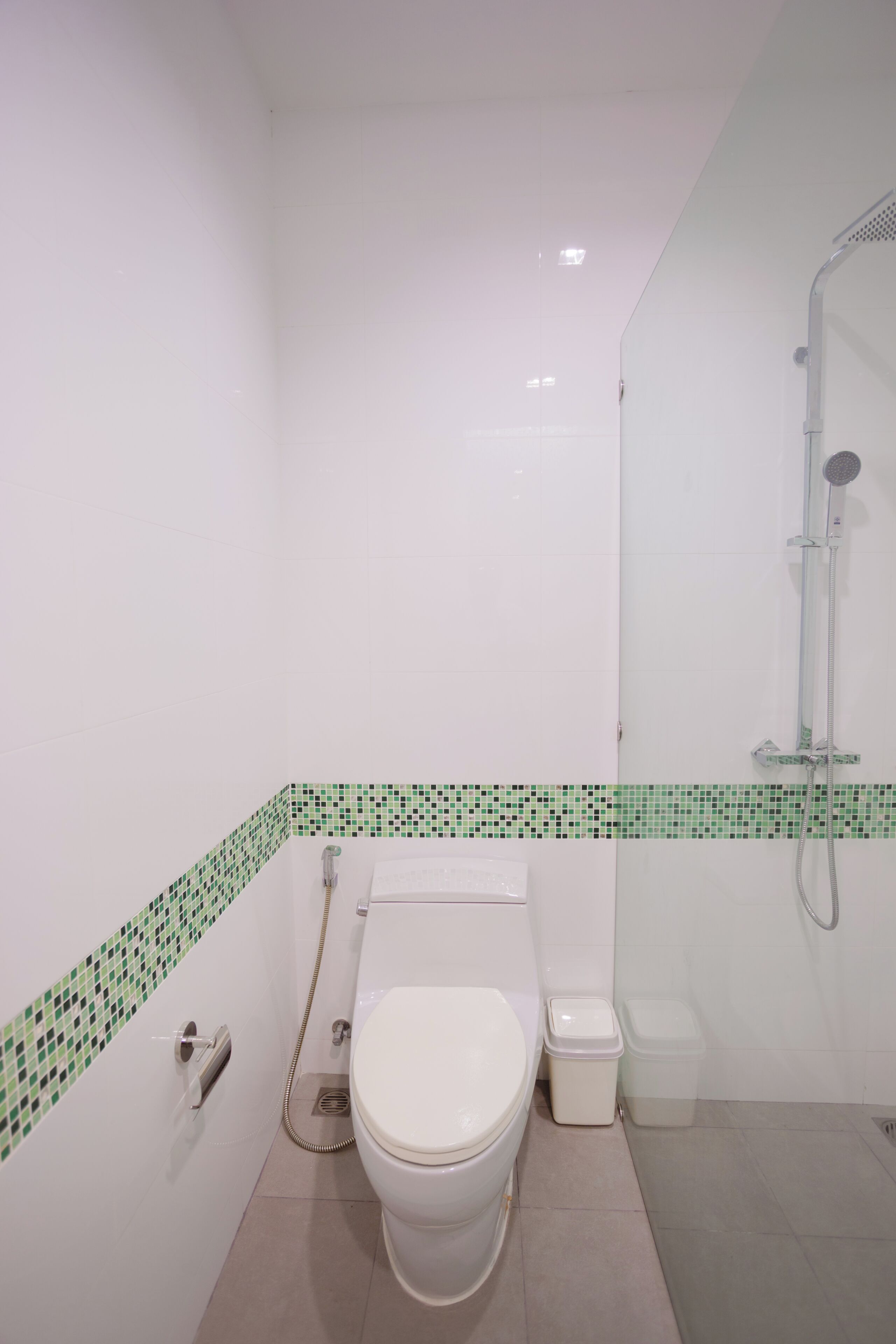 Een badkamer met toilet, douche en prullenbak.