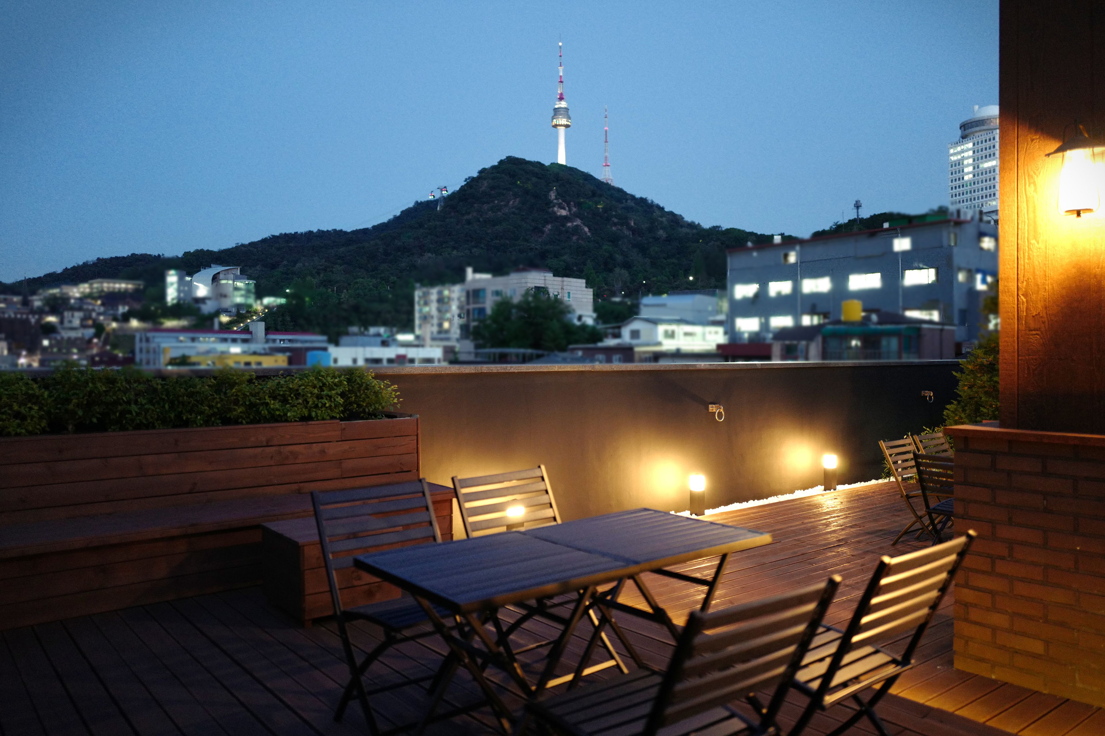 An outdoor seating area with a view of a cityscape and a hill with a tower.