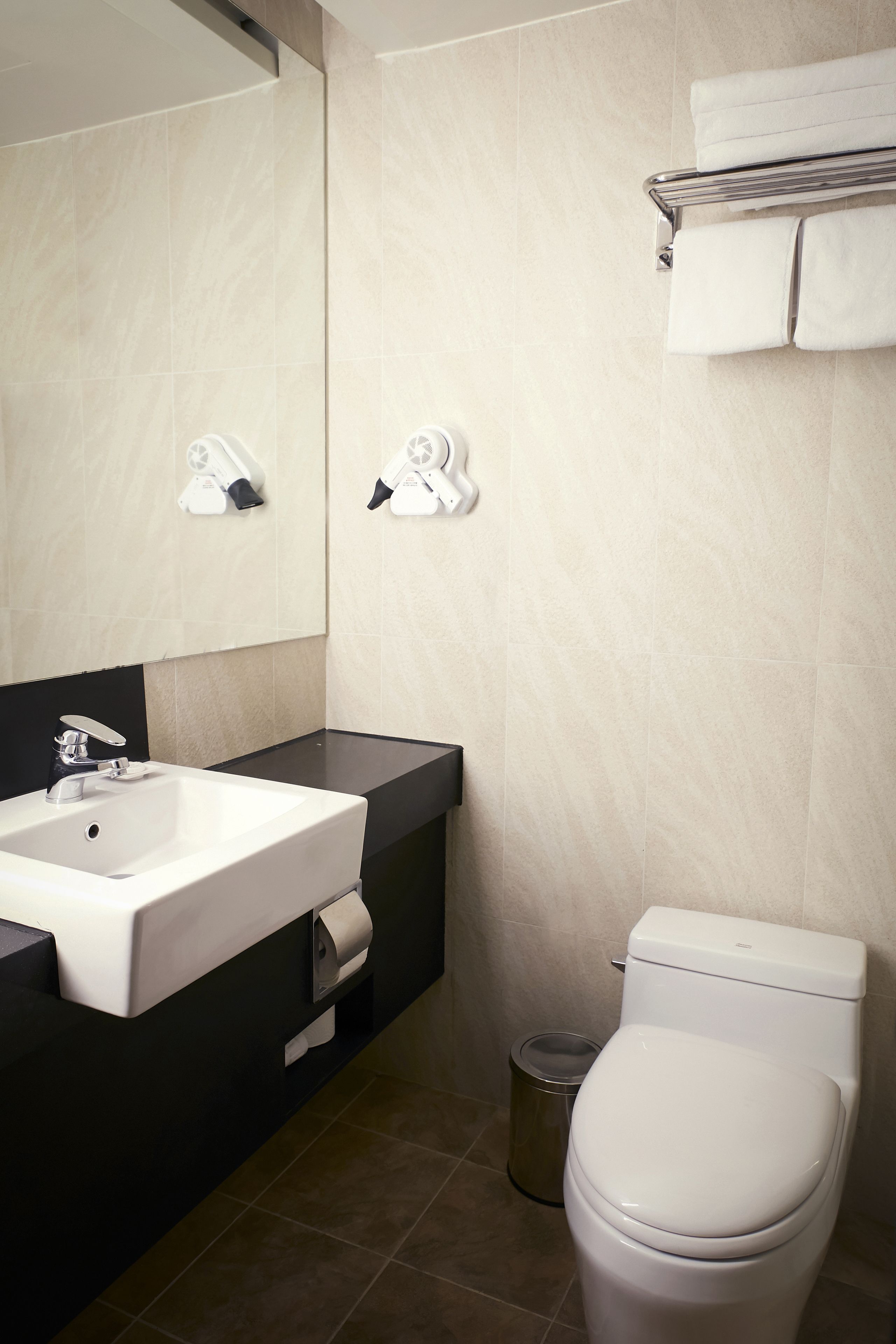 Een moderne badkamer met een witte wastafel, een zwart aanrecht en een wit toilet.