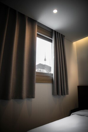 Une chambre d’hôtel avec un lit, une fenêtre avec des rideaux et une vue sur une tour.