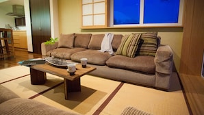 A living room with a brown sofa, a wooden coffee table, and a tatami mat floor. - Tamo (Kutchan)