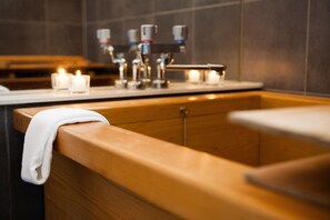 A modern bathroom with a wooden vanity, a sink, and a mirror. There are candles on the counter. - Tamo (Kutchan)