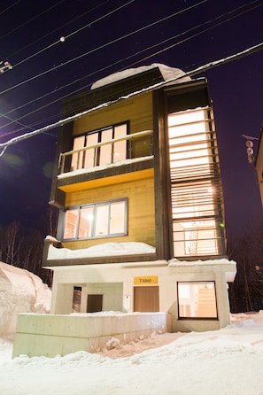 A multi-story building with a sign reading "TAMO" on the ground floor. - Tamo (Kutchan)