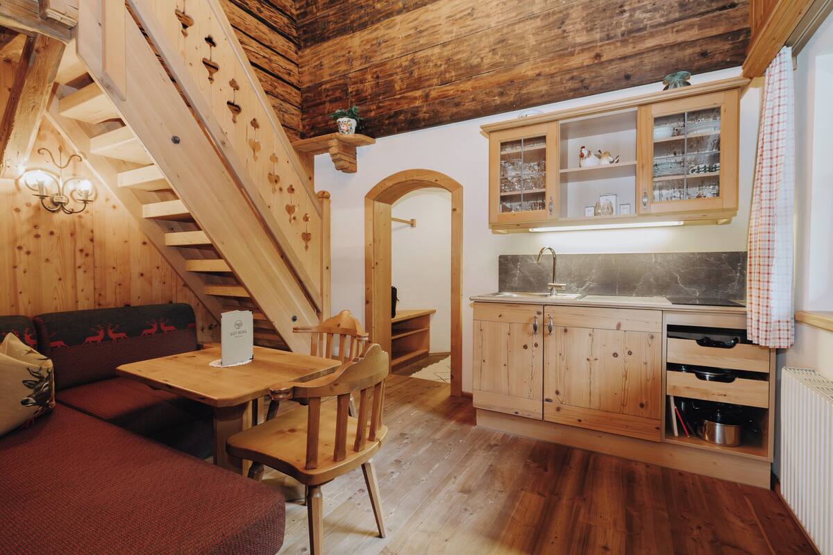 A wooden interior with a staircase, a dining area, and a kitchen with wooden cabinets.