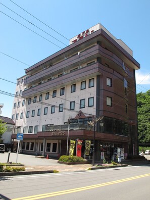 Ein mehrstöckiges Hotel mit modernem Design, mit Balkonen in jeder Etage und einem Eingangsbereich im Erdgeschoss.