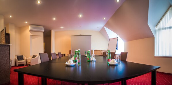 A conference room with a long table, chairs, and green bottles of water. - Hotel West (Bratislava)