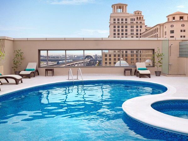 Una piscina al aire libre, sombrillas, sillones reclinables de piscina