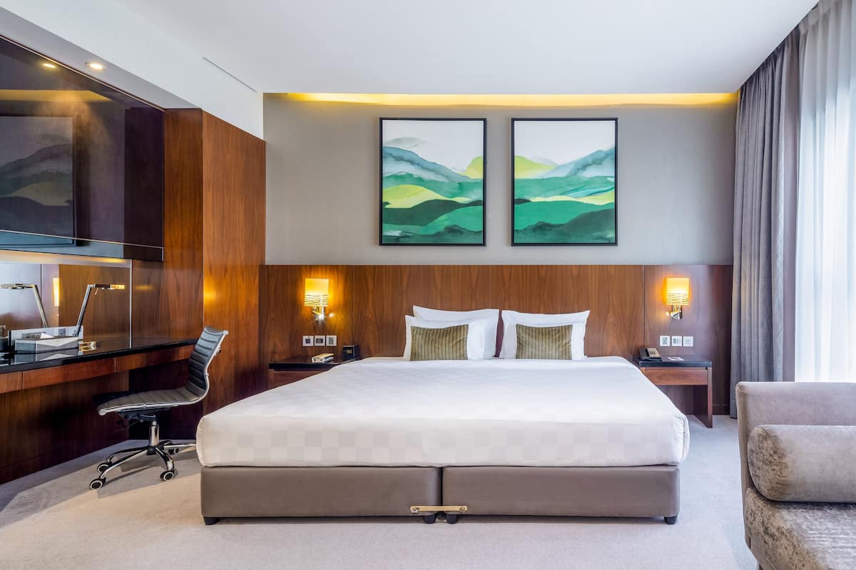 Una habitación de hotel moderna con una cama grande, un escritorio con una silla y dos lámparas de noche.