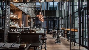 A modern bar with a high ceiling, exposed ductwork, and a variety of bar tools and bottles. - Hotel Proverbs Taipei (Taipei)