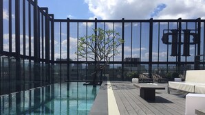 A rooftop pool area with a clear view of the city skyline, a wooden deck, and lounge seating. - Hotel Proverbs Taipei (Taipei)