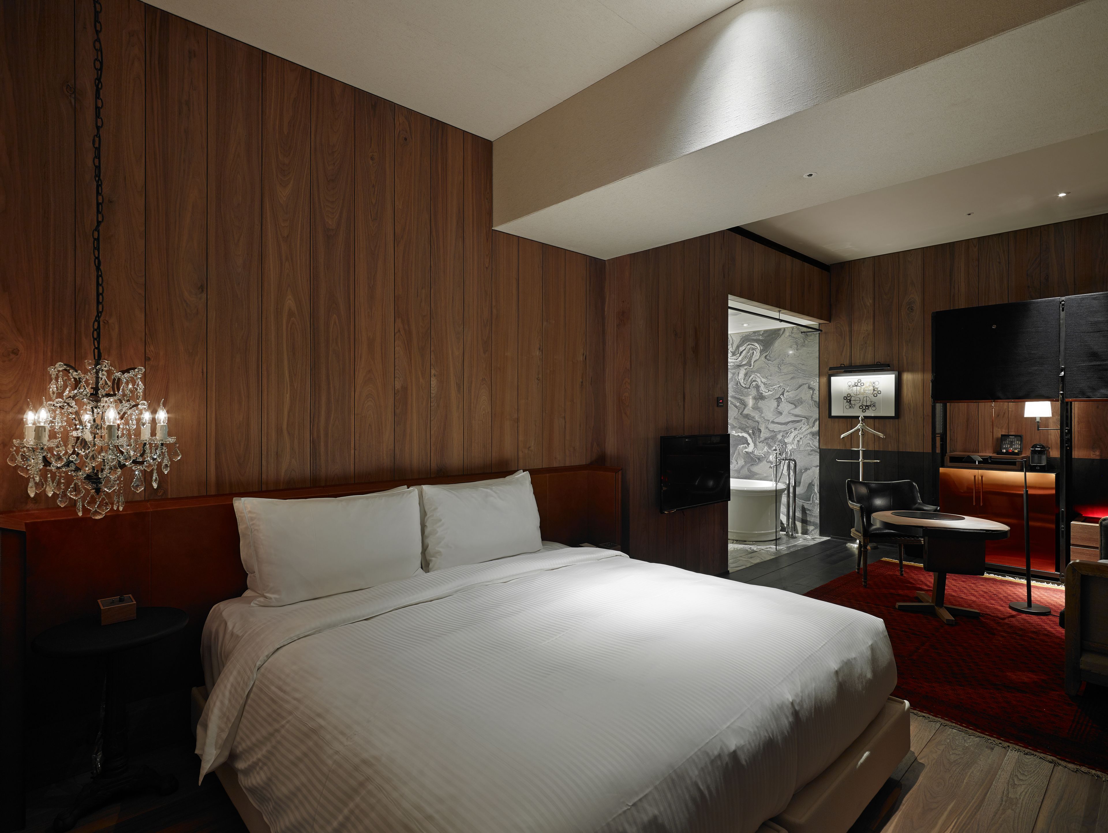 Une chambre moderne avec un grand lit, un lustre et un téléviseur.