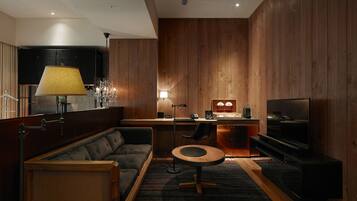 A modern living room with a sofa, a coffee table, a TV, and a desk with a lamp.