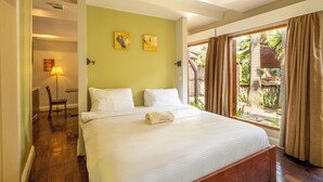 A hotel room with a large bed, a desk, and a chair. There are two paintings on the wall and a window with curtains. - Olma Hotel & Suites (Accra)