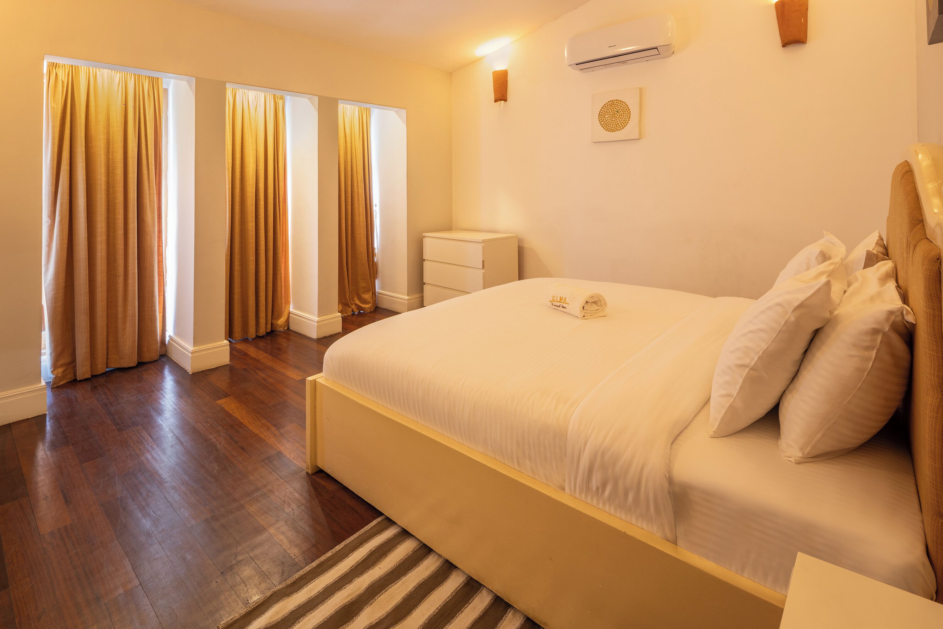 Un dormitorio con una cama grande, una mesita de noche y un aire acondicionado instalado en la pared.