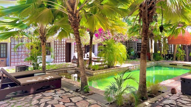 A pool area with lounge chairs, palm trees, and a stone pathway. - Olma Hotel & Suites (Accra)