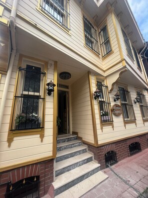Un bâtiment à deux étages, doté d’une façade beige, d’une cheminée en briques et d’une enseigne indiquant « Élégance ottomane ».