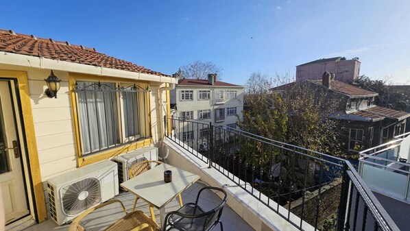 Un balcon équipé d’une table, de chaises et d’un appareil de climatisation.