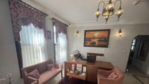 A living room with a sofa, armchairs, a coffee table, and a laptop. There is a painting on the wall and a chandelier. - Ottoman Elegance Hotel (Istanbul)