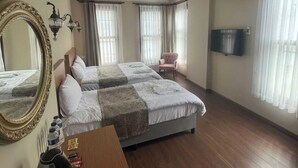 A hotel room with two beds, a desk, a chair, a large mirror, and a TV. - Ottoman Elegance Hotel (Istanbul)