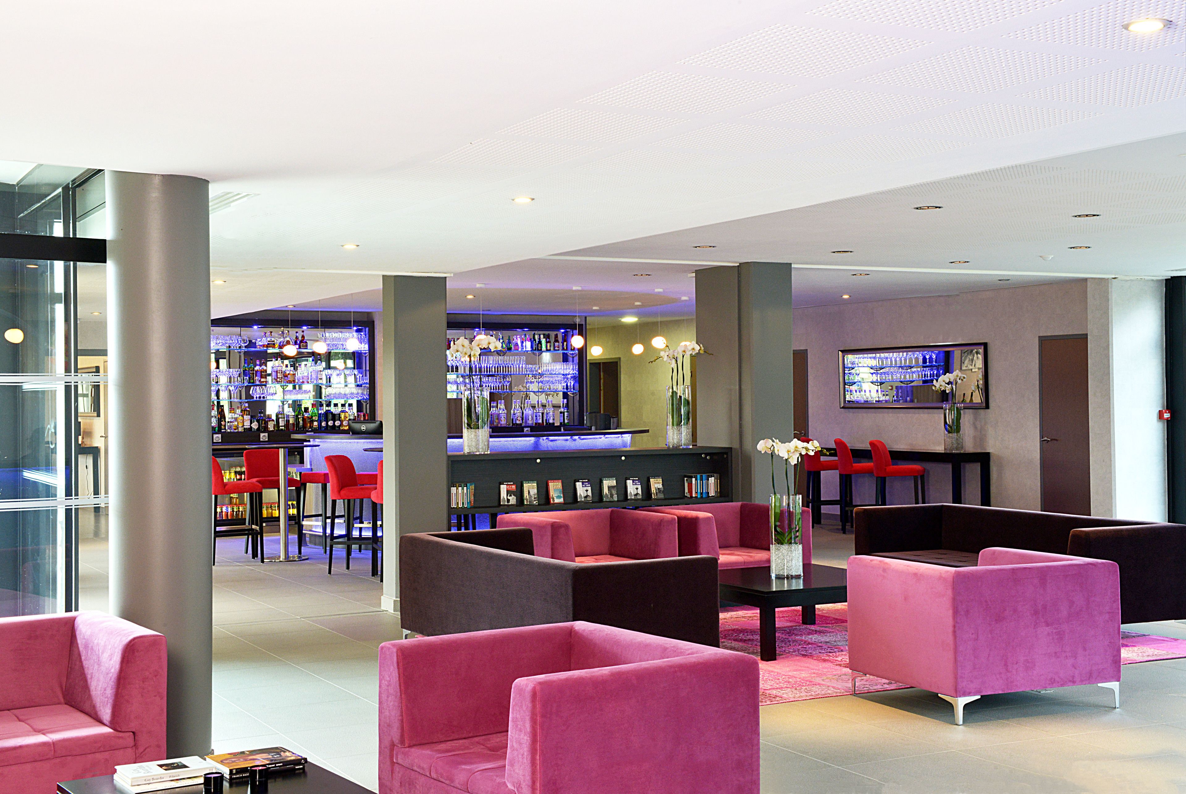 A modern lobby with a bar area, seating, and a television screen.