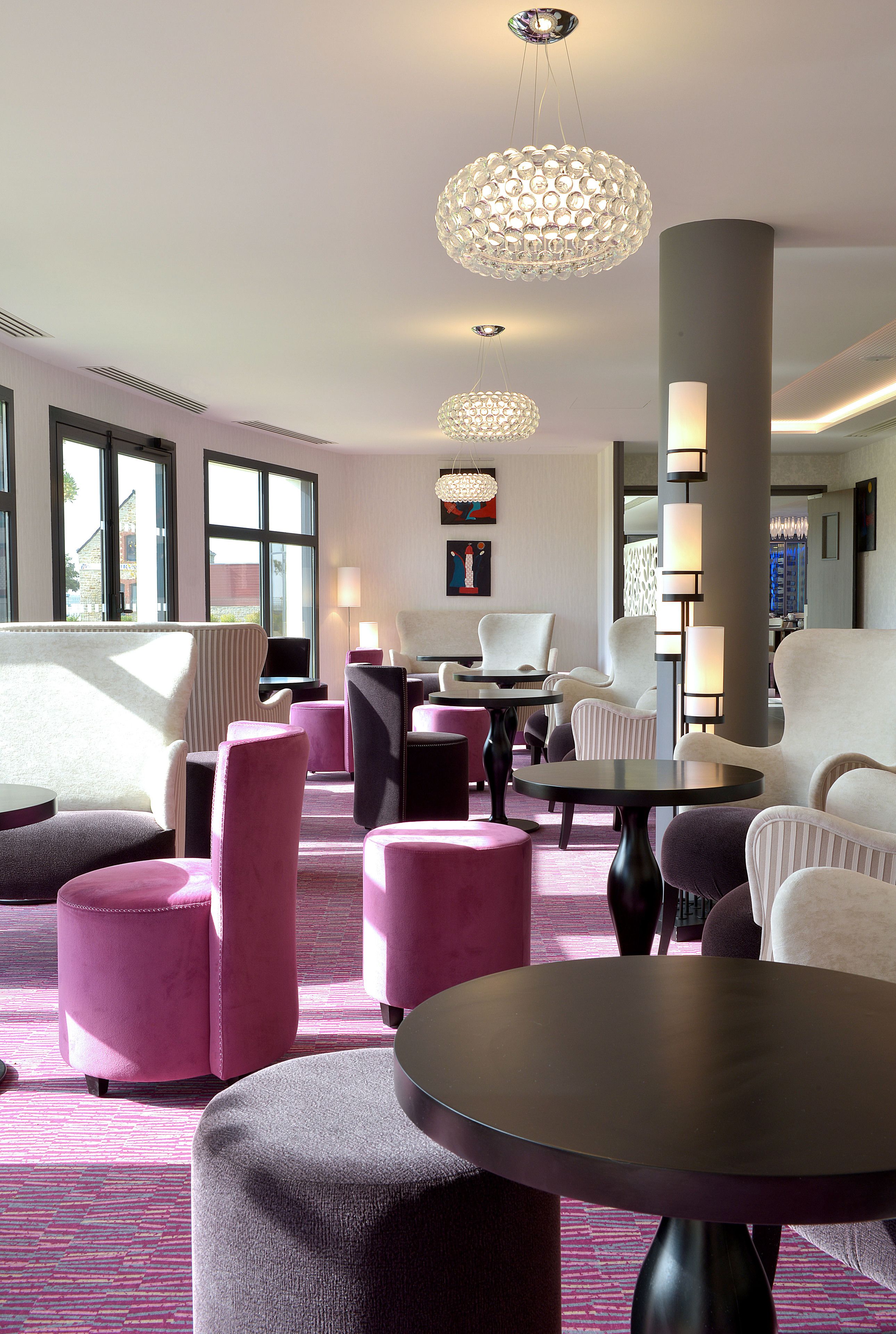 Un moderno vestíbulo de hotel con asientos cómodos, ventanas amplias y luminarias contemporáneas.