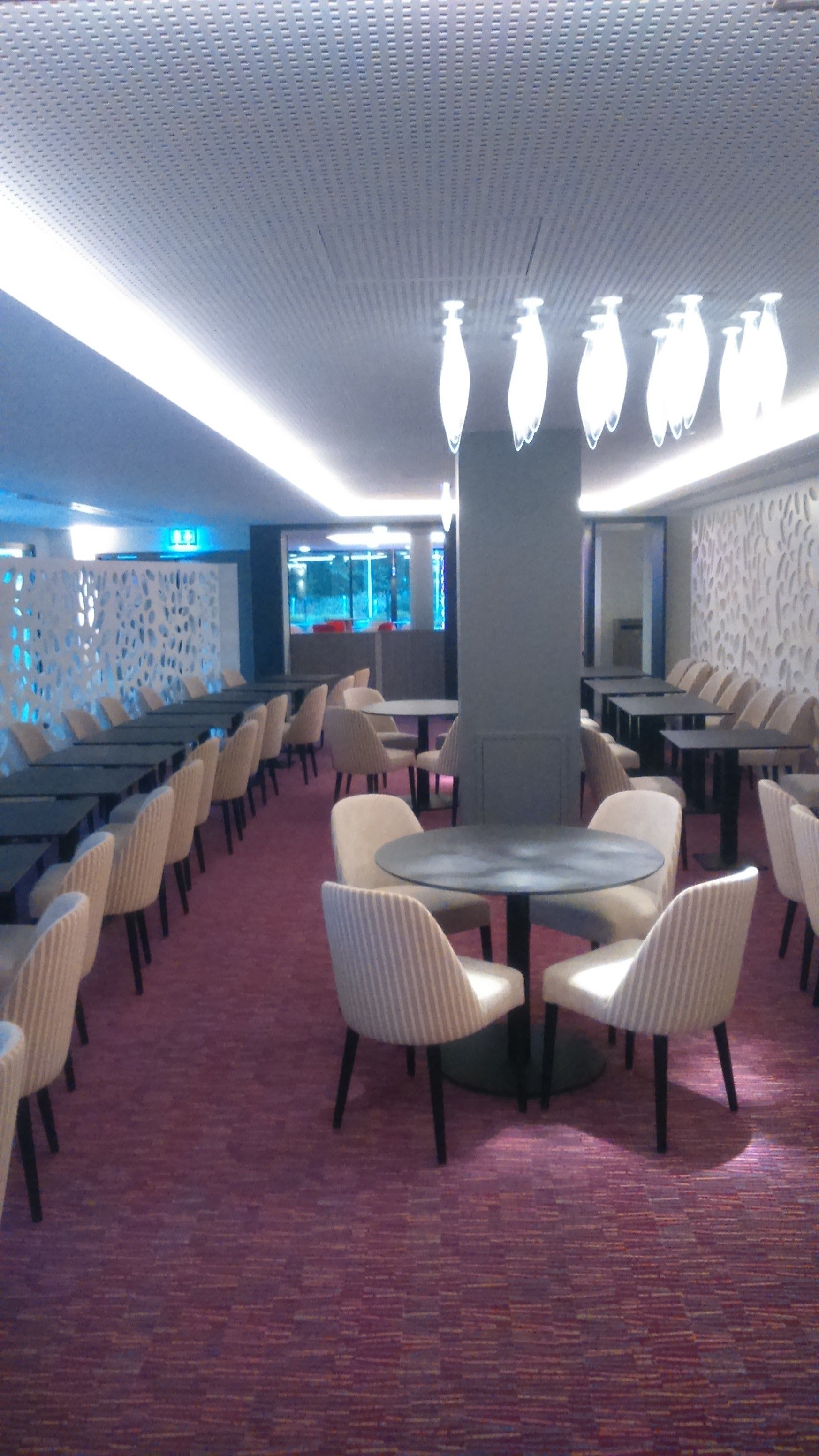 A conference room with a large central table surrounded by chairs, a patterned ceiling, and a carpeted floor.