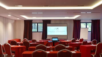 A conference room with red tables and chairs, a projector screen displaying 'THALASSO CONCARNEAU SPA MARIN RESORT', and a laptop on a table.