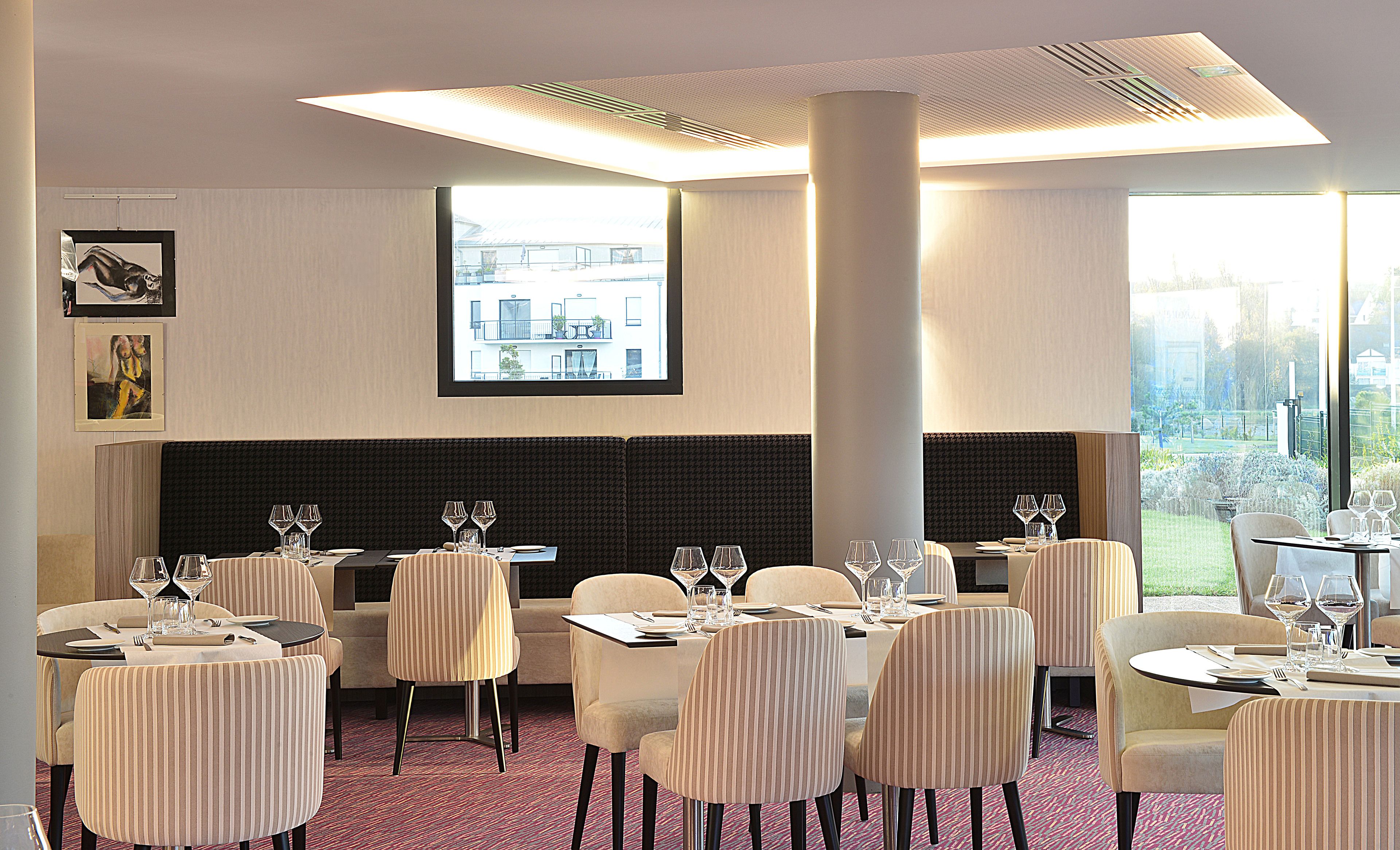 A restaurant with tables set for dining, a large window with a view, and a modern ceiling design.