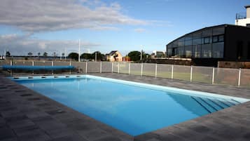 Relax by the clear pool surrounded by a deck and a building with a curved facade.