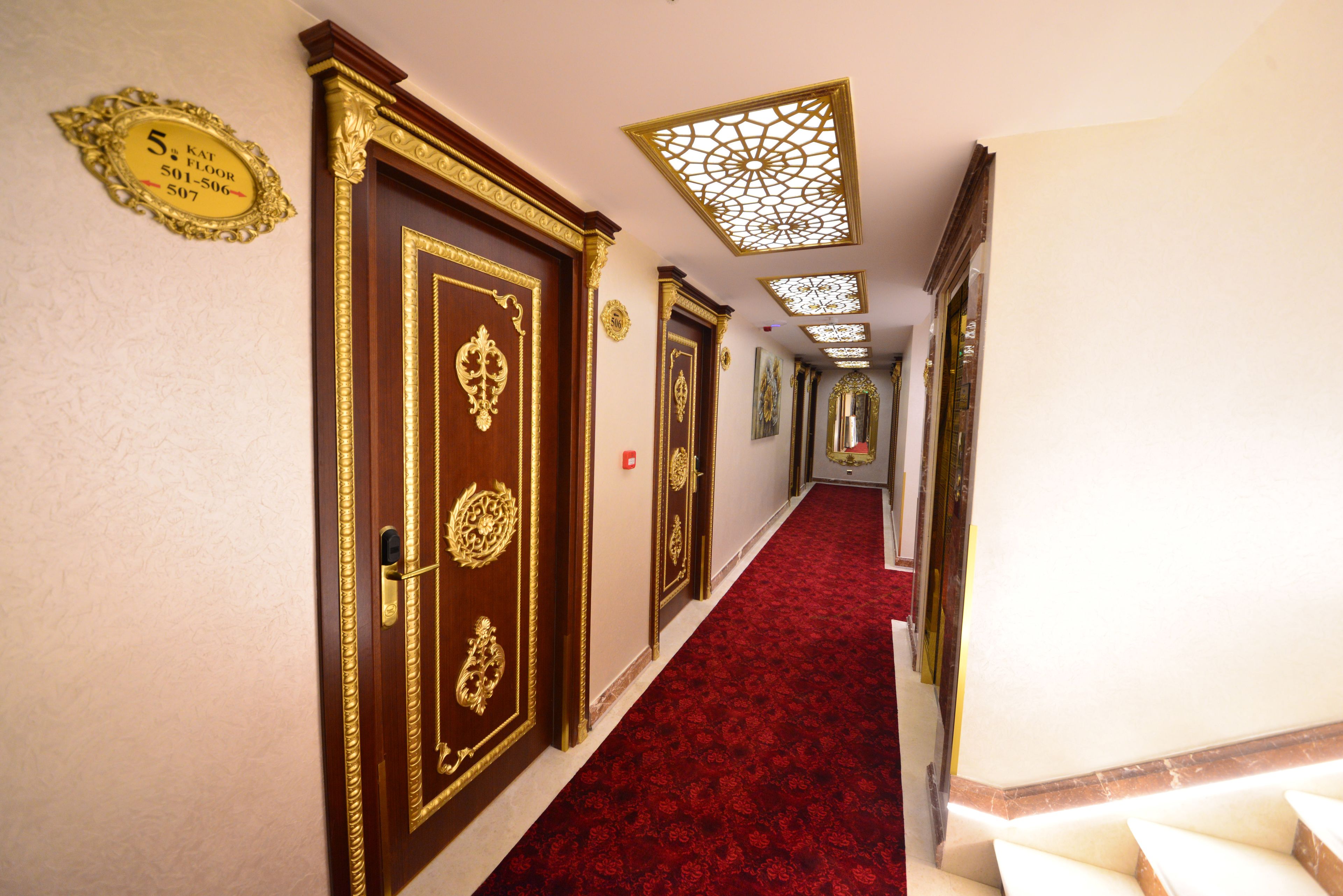 A hallway with ornate doors, a red carpet, and a ceiling with decorative panels.