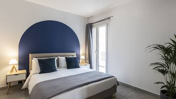 Un dormitorio con cama, mesitas de noche, una planta en maceta y vistas al exterior.