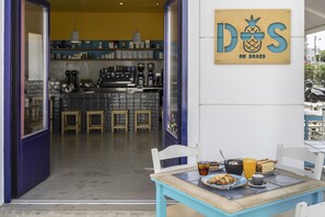 Un coin repas avec une table mise pour le petit-déjeuner, une machine à café et un panneau indiquant : « DOS ON BOARD ».