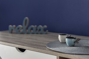 A wooden table with two ceramic cups and a decorative word "relax" on a blue background.