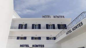 Um hotel chamado HOTEL KONTES com fachada branca e várias varandas.