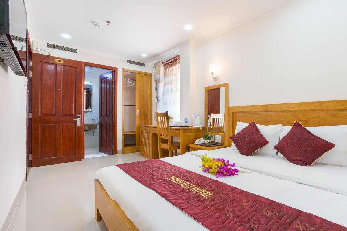 A hotel room with a bed, a desk, and a wardrobe.