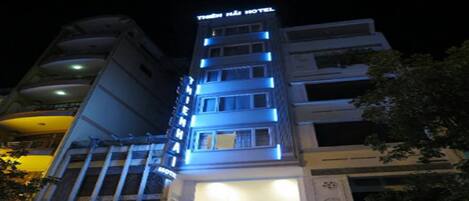 Un hotel con varios pisos, señalización iluminada y una entrada visible.