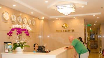 A hotel reception area with a reception desk, a clock, and a sign that reads "THIEN HAI HOTEL".