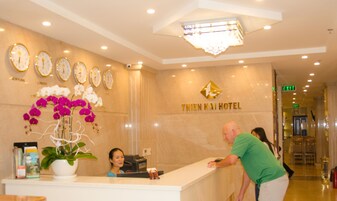 A hotel reception area with a reception desk, a clock, and a sign that reads "THIEN HAI HOTEL".