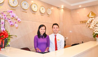 A reception desk with clocks displaying times from various cities, a floral arrangement, and a security camera.