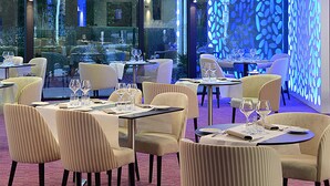 En restaurant med borde dækket til spisning, stole og udsigt over naturen.