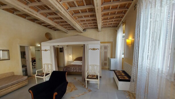 A spacious room with a high ceiling, a bed with a canopy, a sofa, and a chair. - Residenza al Corso (Rome)