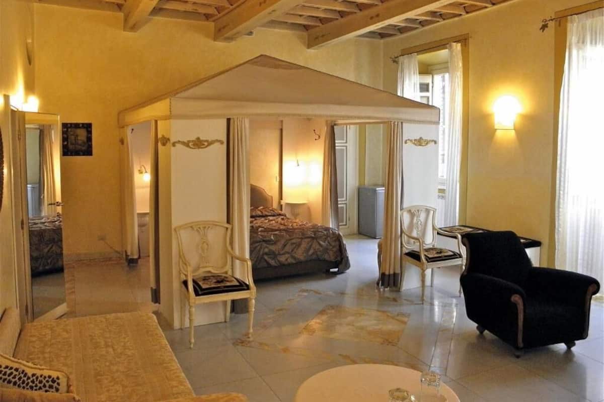 Una habitación amplia con cama, dos sillas, una mesa y un ventanal grande.