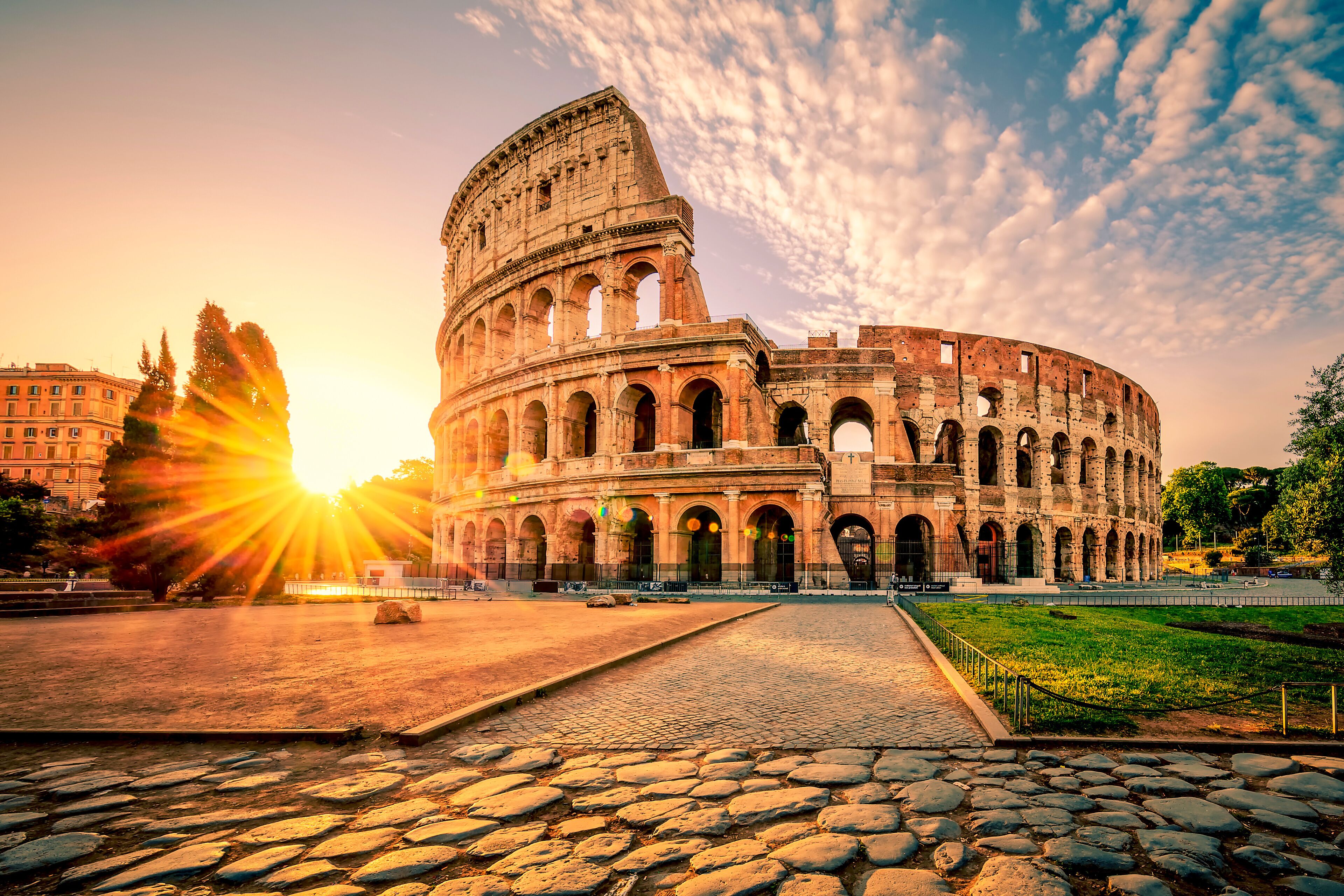 A historic coliseum with a cobblestone pathway leading to its entrance.