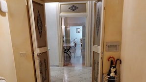 A hallway with a bed, a chair, and a metal rack with umbrellas. - Residenza al Corso (Rome)