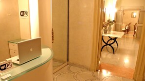 A hotel reception area with a glass desk, a laptop, and a Wi-Fi sign. - Residenza al Corso (Rome)