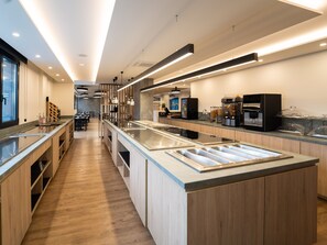 A modern kitchen with a long counter, built-in appliances, and a view of the dining area. - Hotel Las Terrazas (Burgos)
