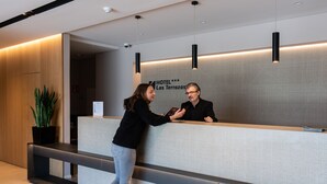 A hotel reception desk with a modern design, a potted plant, and a sign indicating the hotel name. - Hotel Las Terrazas (Burgos)
